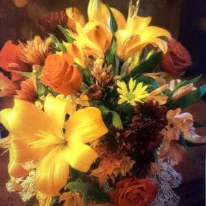 A vibrant bouquet of yellow lilies, orange roses, and various flowers.
