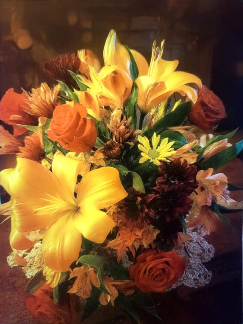 A vibrant bouquet of yellow lilies, orange roses, and various flowers.